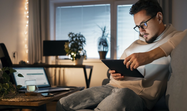 Homem mexendo no tablet em casa. 